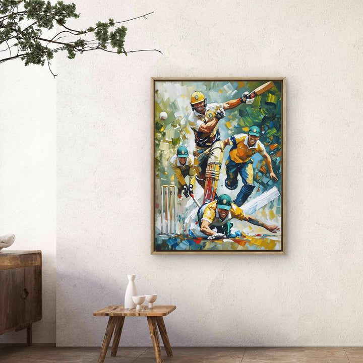 Framed artwork of a cricket match scene on a wall in a room with a wooden cabinet and plant.