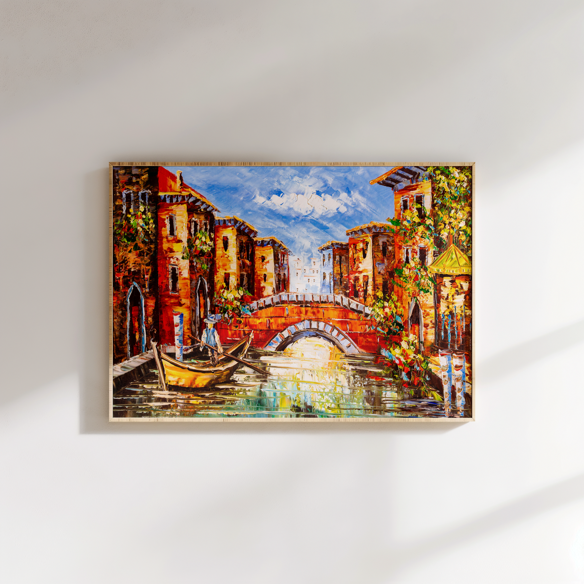 Framed painting of a canal scene with buildings and boats on a white wall.